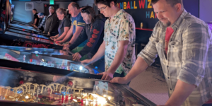 a group of people playing pinball machines