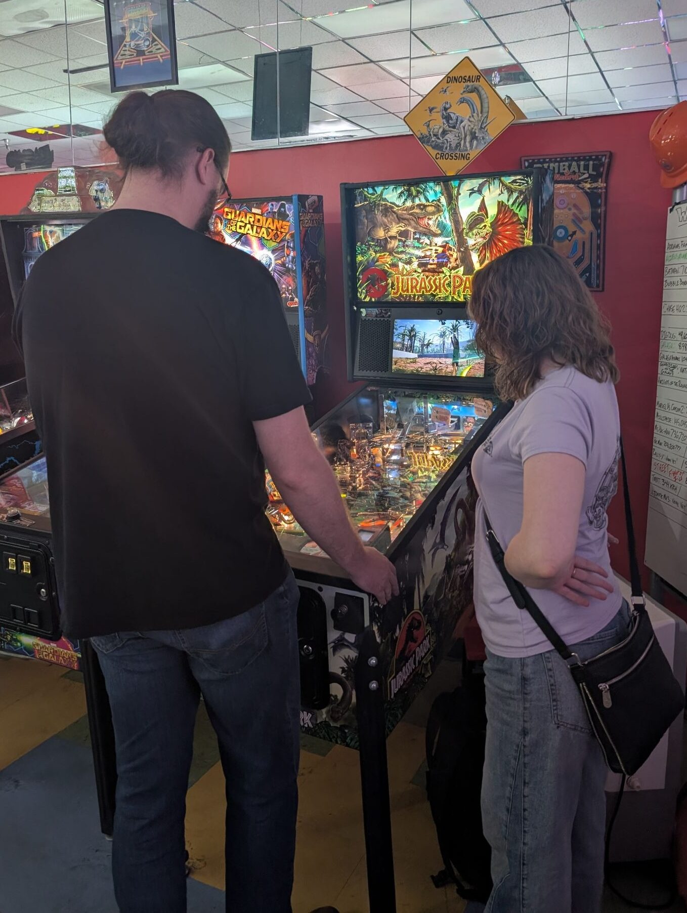 A person standing very close to their opponent's right side, directly next to the pinball machine. 